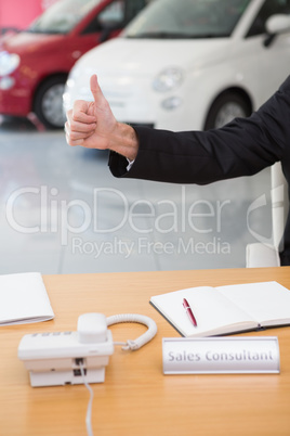 Close up of businessman giving thumbs up at his desk