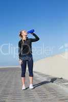 Fit blonde drinking water on the pier