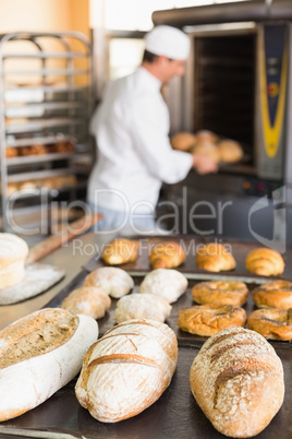 Happy baker taking out fresh loaves