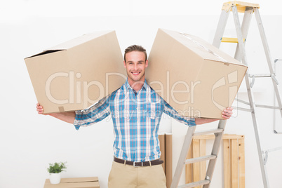 Smiling man carrying cardboard moving boxes