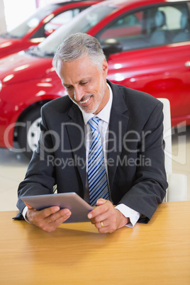 Smiling businessman using tablet at his desk