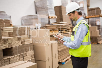 Warehouse worker checking his list on clipboard