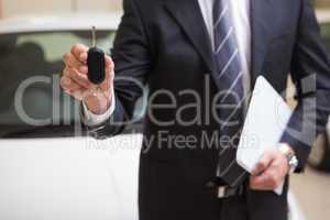 Businessman showing a car key while holding clipboard