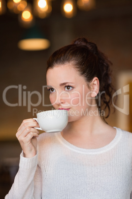 Pretty brunette sipping cup of coffee