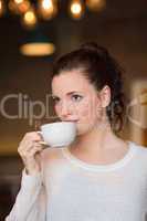 Pretty brunette sipping cup of coffee