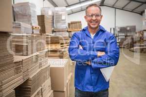 Smiling warehouse manager standing with arms crossed