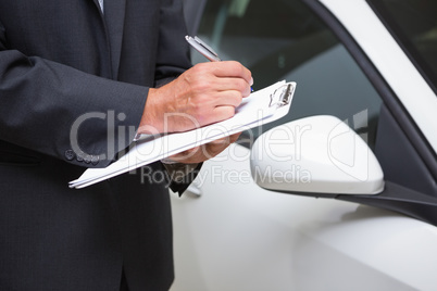 Close up of businessman writing on clipboard