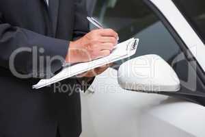 Close up of businessman writing on clipboard