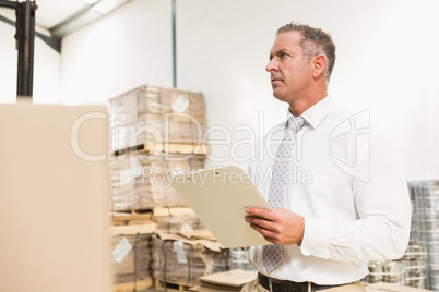 Warehouse manager checking his list on clipboard