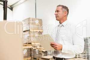 Warehouse manager checking his list on clipboard