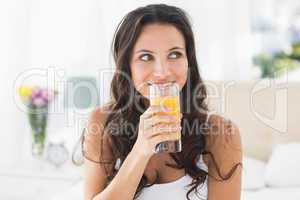 Happy brunette having glass of orange