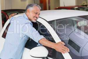 Smiling man hugging a white car