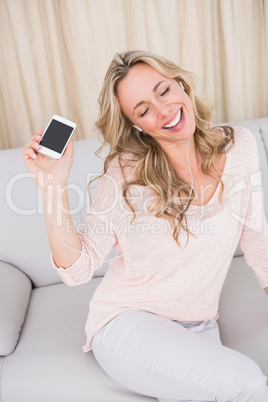 Smiling blonde listening music with earphones