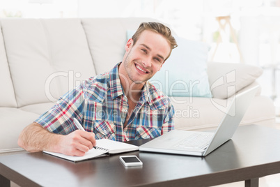 Smiling man writing on a notebook