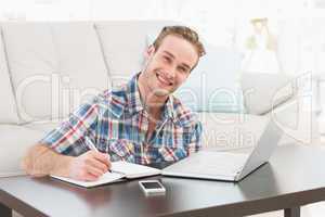 Smiling man writing on a notebook