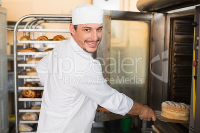 Happy baker taking out fresh loaf