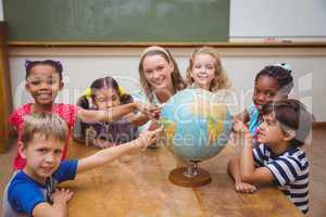 Cute pupils and teacher in classroom with globe