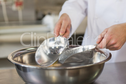 Baker holding scoops over bowl