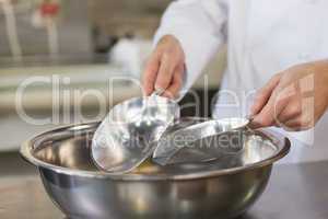 Baker holding scoops over bowl