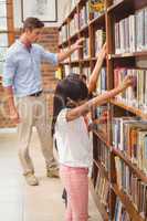 Cute pupils and teacher looking for books in library