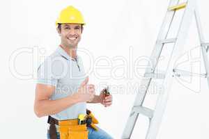 Technician with tools showing thumbs up by step ladder