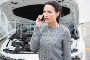 Annoyed woman on the phone beside her broken down car