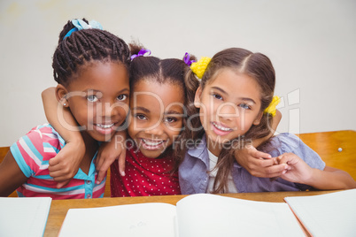 Cute pupils smiling at camera in classroom