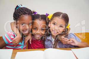 Cute pupils smiling at camera in classroom