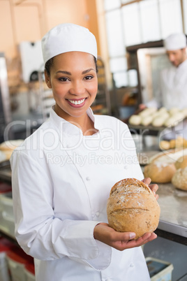 Pretty baker smiling at camera with loaf