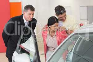 Car dealer showing the interior of a car to a couple