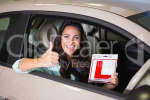 Woman gesturing thumbs up holding a learner driver sign