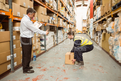 Manager watching worker carrying boxes