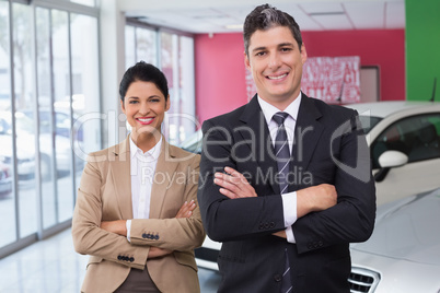 Smiling colleagues standing with arms crossed Smiling colleagues standing with arms crossed