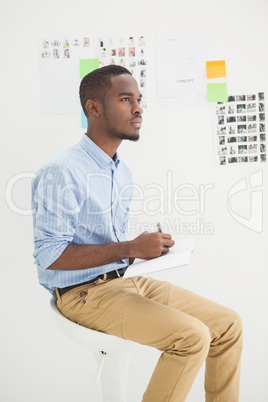 Thoughtful businessman sitting writing on notebook