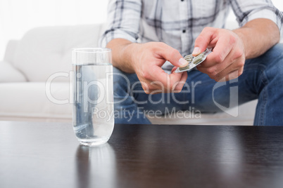 Hungover man with his medicine laid out on coffee table