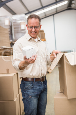 Smiling warehouse worker holding small box