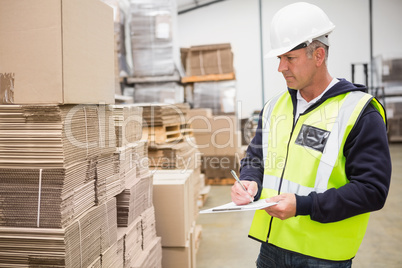 Warehouse worker checking his list on clipboard