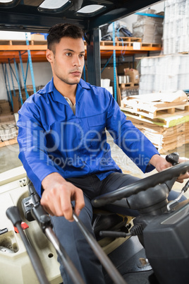 Driver operating forklift machine in warehouse