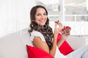 Pretty brunette eating strawberries on couch