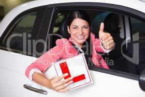 Woman gesturing thumbs up holding a learner driver sign