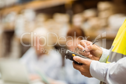 Close up of manager wearing yellow vest using handheld