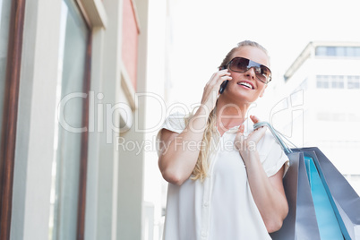 Pretty blonde making a call holding shopping bags Pretty blonde making a call holding shopping bags