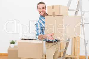 Smiling man carrying cardboard moving boxes