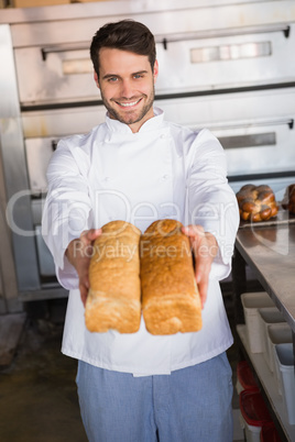 Smiling baker showing loaves of bread