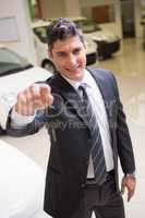 Salesman standing while offering car keys