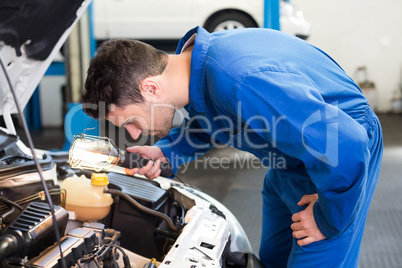 Mechanic examining under hood of car with torch