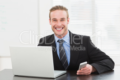 Classy businessman using laptop and mobile phone