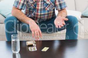 Man sitting on sofa holding pills