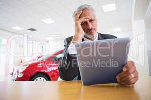 Upset businessman using tablet at his desk