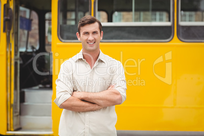 Smiling bus driver standing with arms crossed